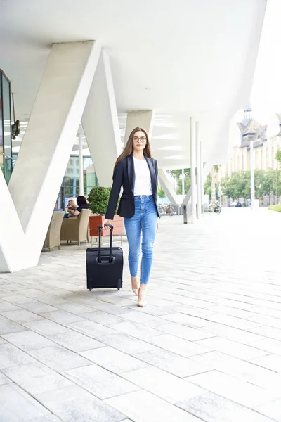 Full length shot of young businesswoman walking with her luggage after checked out from hotel.