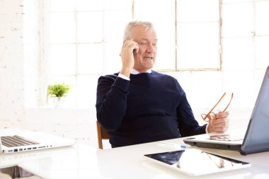 Üst düzey işadamı nın ofis masasında dizüstü bilgisayarın önünde oturup cep telefonundan biriyle konuşması vuruldu. 