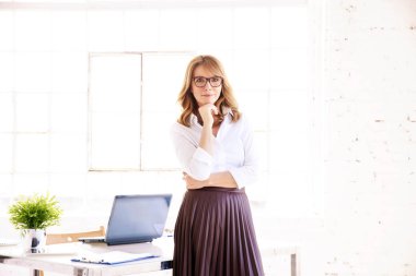 Ofisteki masada kameraya bakıp gülümseyen çekici orta yaşlı kadın.. 