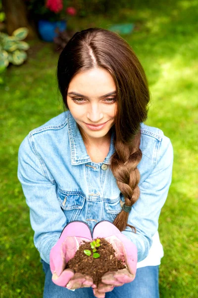 Zbliżenie Piękną Młodą Kobietę Rękawiczkach Trzymającą Roślinę Wyrastającą Ziemi Rękach — Zdjęcie stockowe