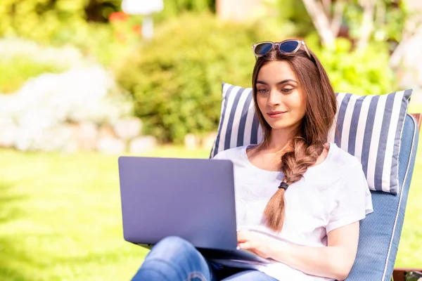Tiro Jovem Mulher Sentada Leito Solar Jardim Usando Seu Laptop — Fotografia de Stock