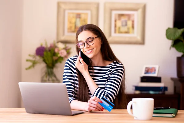 在家里工作的时候 坐在笔记本电脑后面打电话给一个快乐的年轻女人 总部办公室 — 图库照片