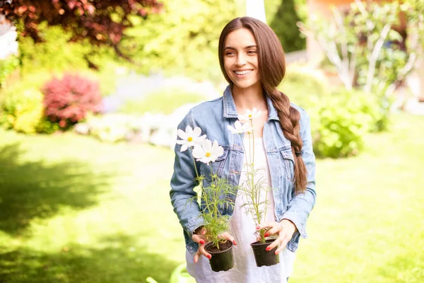 自宅で庭をしながら 彼女の手に鉢植えの花を保持美しい若い女性のショット — ストック写真