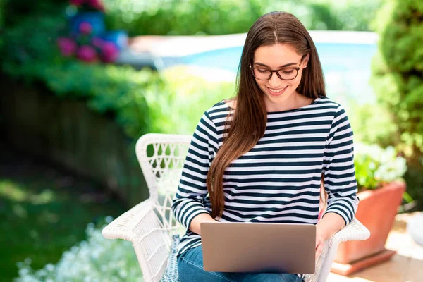 自宅のバルコニーに座ってオンラインで作業しながら 彼女のラップトップを使用して笑顔の若い女性のショット 内務省 — ストック写真