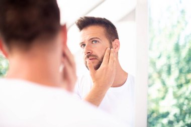 Banyodaki aynada yüzüne hayran olan yakışıklı bir gencin yakın plan fotoğrafı..