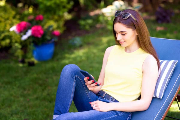 Evde Dinlenirken Cep Telefonu Mesajlarıyla Gülümseyen Genç Bir Kadının Fotoğrafı — Stok fotoğraf