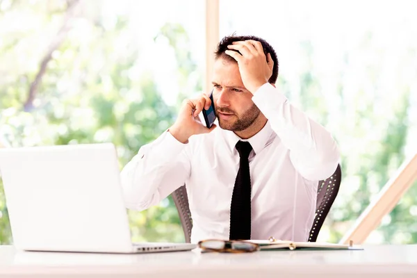 Stresli Adamının Laptopla Çalışırken Ofiste Otururken Cep Telefonuyla Konuşurken Çekilmiş — Stok fotoğraf