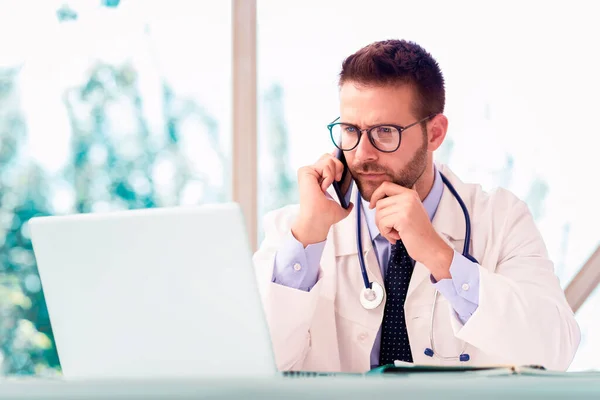 Egy Férfi Orvos Ült Asztalánál Laptopja Mögött Mobilon Beszélt Betegével — Stock Fotó