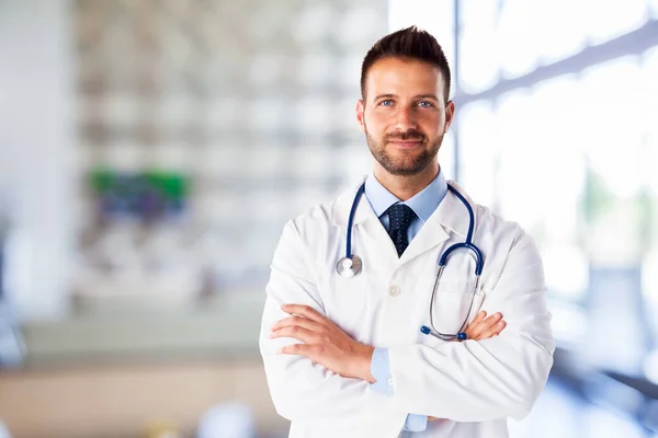 一个面带微笑的男医生双手交叉地站在医院门廊上的画像 — 图库照片