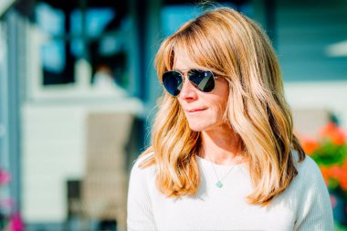 Evdeki bahçede dinlenirken orta yaşlı bir kadının güneş gözlüğü taktığı yakın plan bir portre resmi.. 