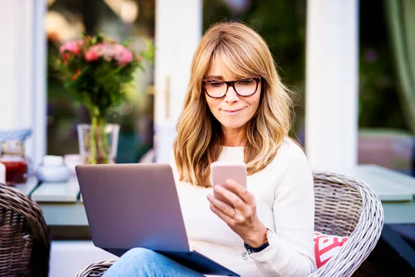 Porträtt Medelålders Kvinna Med Bärbar Dator Och Textmeddelanden När Arbetar — Stockfoto