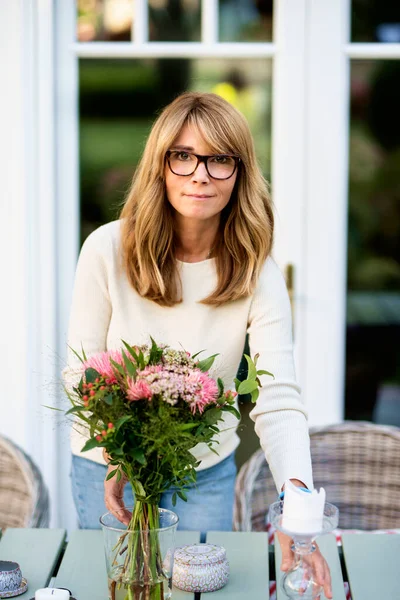 Arca Vonzó Középkorú Áll Erkélyen Otthon Miközben Elrendezi Virágok Asztalon — Stock Fotó