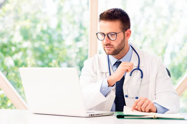 Přemýšlející Mužský Lékař Sedí Svým Laptopem — Stock fotografie