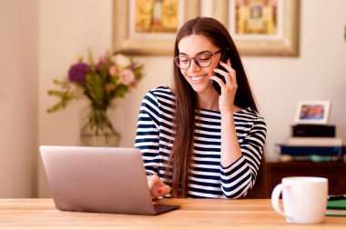 Mutlu iş kadını evde dizüstü bilgisayarla çalışırken iş görüşmesi yapıyor. Merkez Ofis.
