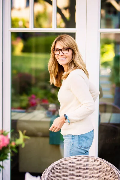 照片中 一位自信的成熟女子站在花园阳台的前门 — 图库照片