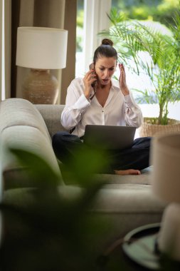 Evde dizüstü bilgisayar ve akıllı telefon kullanan orta yaşlı bir kadın. Kendine güvenen bir kadın arabada oturuyor ve evde çalışıyor. Merkez Ofis. 