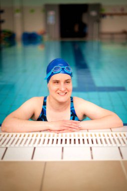 Yüzme havuzunda yüzme şapkası ve gözlük takan görme engelli bir kadın. Sağlık ve eğlence faaliyetleri. Yakın çekim.. 