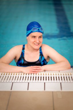 Yüzme havuzunda yüzme şapkası ve gözlük takan görme engelli bir kadın. Sağlık ve eğlence faaliyetleri. Yakın çekim.. 