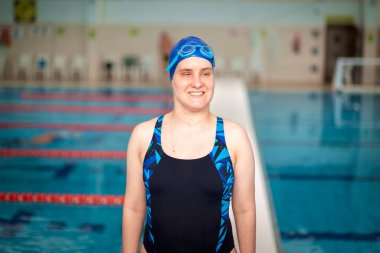 Yüzme havuzunda yüzme şapkası ve gözlük takan görme engelli bir kadın. Sağlık ve eğlence faaliyetleri. Yakın çekim.. 