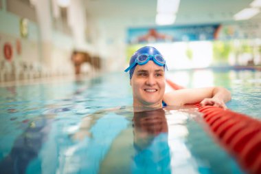 Yüzme havuzunda yüzme şapkası ve gözlük takan görme engelli bir kadın. Sağlık ve eğlence faaliyetleri. Yakın çekim.. 