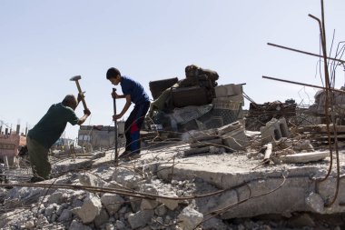 Beit Hanun, Gazze Şeridi/Filistin-Şubat 26 2015: baba ve oğul, altı bir ailenin tek kurtulan, onların roket imha ev demir kurtarmak için çalışmak