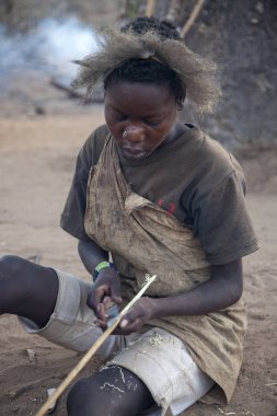 Eyasi Gölü, Arusha/Tanzanya-15 Oct 2014: Hadzabe adamları avcılık yay için yeni oklar hazırlamak