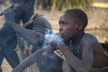 Eyasi Gölü, Arusha/Tanzanya-Oct 15 2014: kabile, erkek ve kadın üyeleri, serbest zaman boyunca ahşap borularda tütün duman