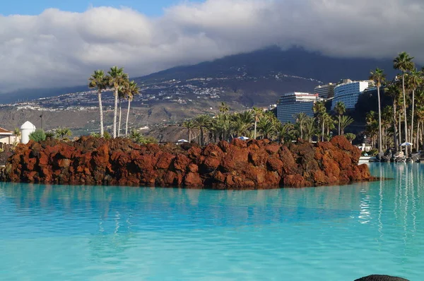 Arka planda turkuaz su ve dağ yamaçlı yüzme havuzu, Tenerife Adası, İspanya 