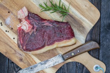 Kuru yaşlı T-bone biftek bir ahşap tahta üzerinde ham.