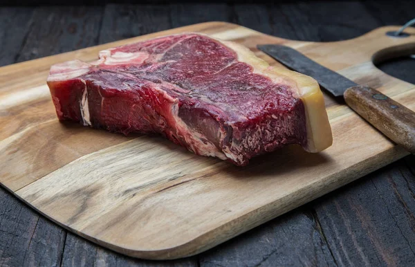 Kuru yaşlı T-bone biftek bir ahşap tahta üzerinde ham.