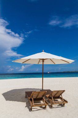 Parasol and sunbeds on the beach Atoll island Maldives. clipart