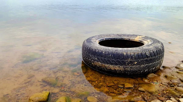 Meio ambiente pneu poluição no lago — Fotografia de Stock