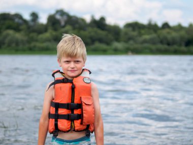 Nehirde yüzme turuncu can yeleği şirin küçük çocuk