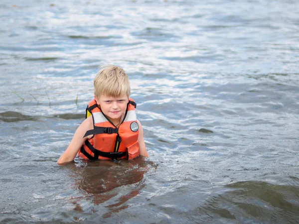 Carino bambino in arancione giubbotto di salvataggio nuotare nel fiume — Foto Stock