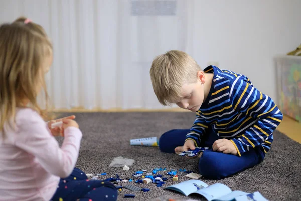 Dos niños jugando con un montón de bloques de plástico de colores constructor . — Foto de Stock