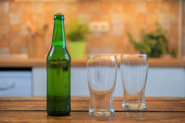 Flaska med öl och tomma glas på bordet — Stockfoto