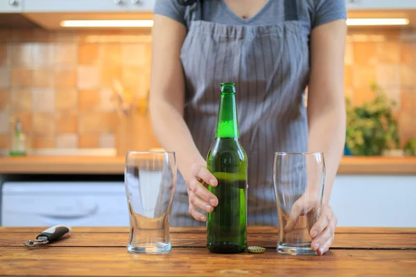Женщина с зеленым бутылкой пива и пустым стаканом — стоковое фото