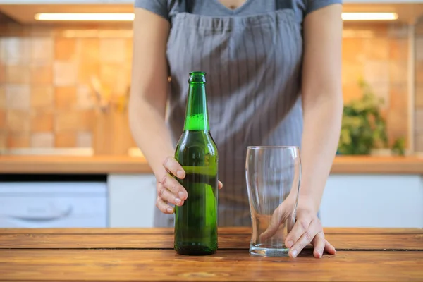 Женщина с зеленым бутылкой пива и пустым стаканом — стоковое фото