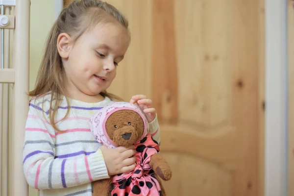 Sonriente niña sosteniendo oso de peluche en el interior — Foto de Stock