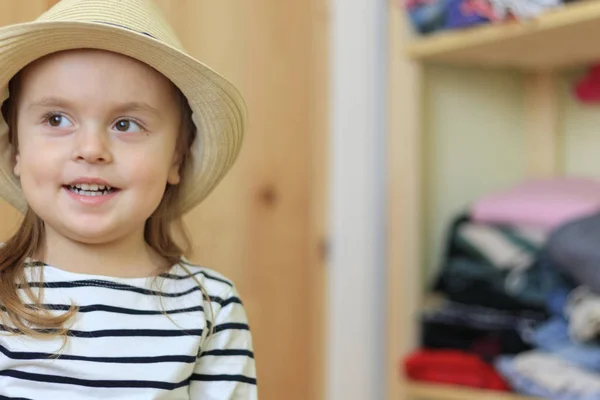 Chica divertida bebé está poniendo en el sombrero en casa — Foto de Stock