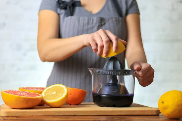 Woman squeezing lemon juice in kitchen — Stock Photo, Image