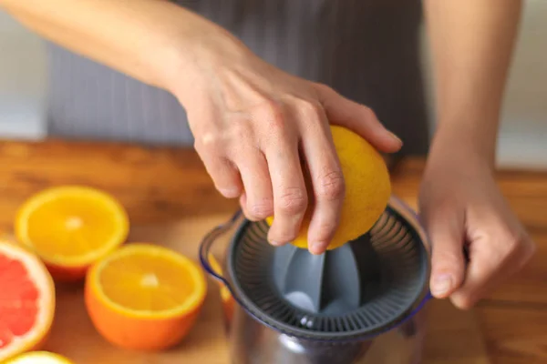 Woman squeezing lemon juice in kitchen — Stock Photo, Image