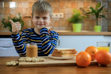 Çocuk fıstık ezmesi ile sandviç yemeye hazırlarken thumbs up gösteriyor