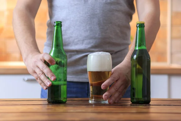 Män håller grön flaska öl och glas på köket — Stockfoto