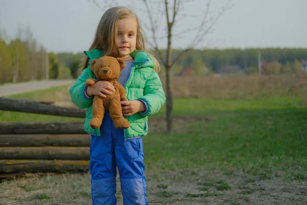 Sonriente niña sosteniendo oso de peluche al aire libre . — Foto de Stock