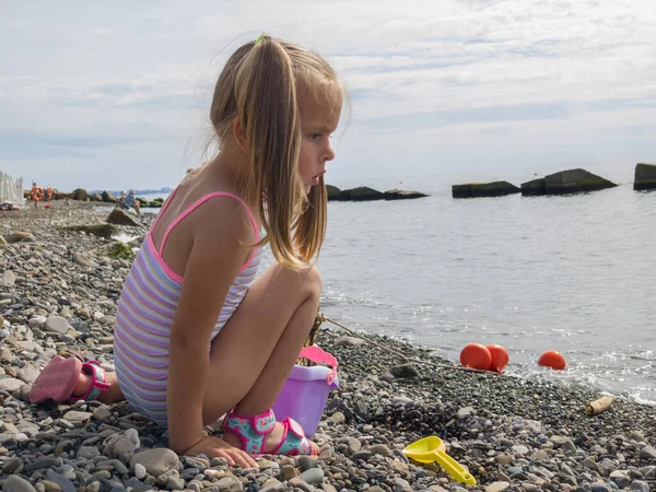 Ragazza carina che gioca con i ciottoli sulla spiaggia — Foto Stock