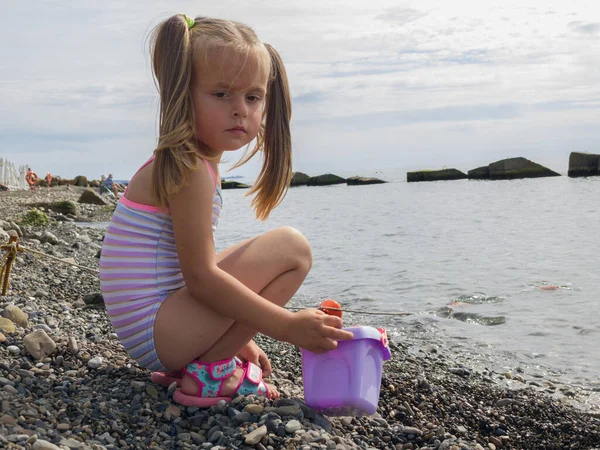 Ragazza carina che gioca con i ciottoli sulla spiaggia — Foto Stock