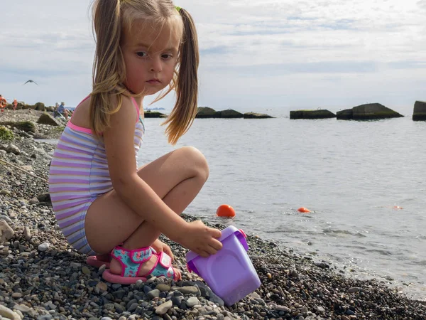 Ragazza carina che gioca con i ciottoli sulla spiaggia — Foto Stock