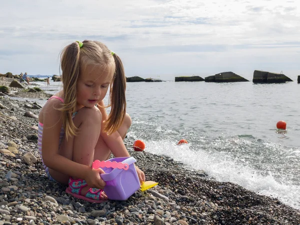 Ragazza carina che gioca con i ciottoli sulla spiaggia — Foto Stock