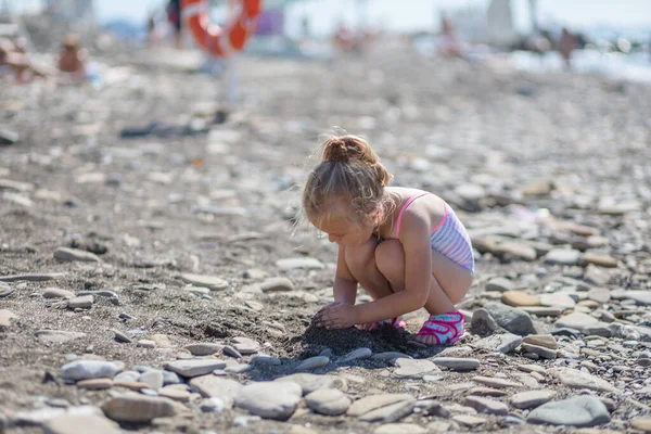 Ragazza carina che gioca con i ciottoli sulla spiaggia — Foto Stock